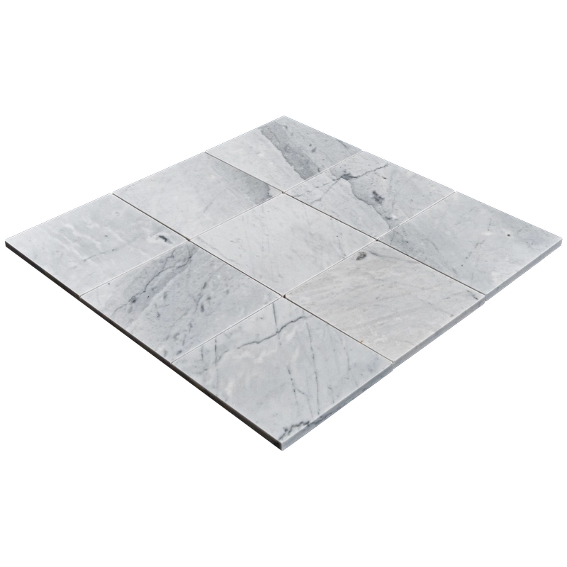 Perspective shot of nine Carrara 6"x6" honed marble tiles arranged in a square layout on a dark background.