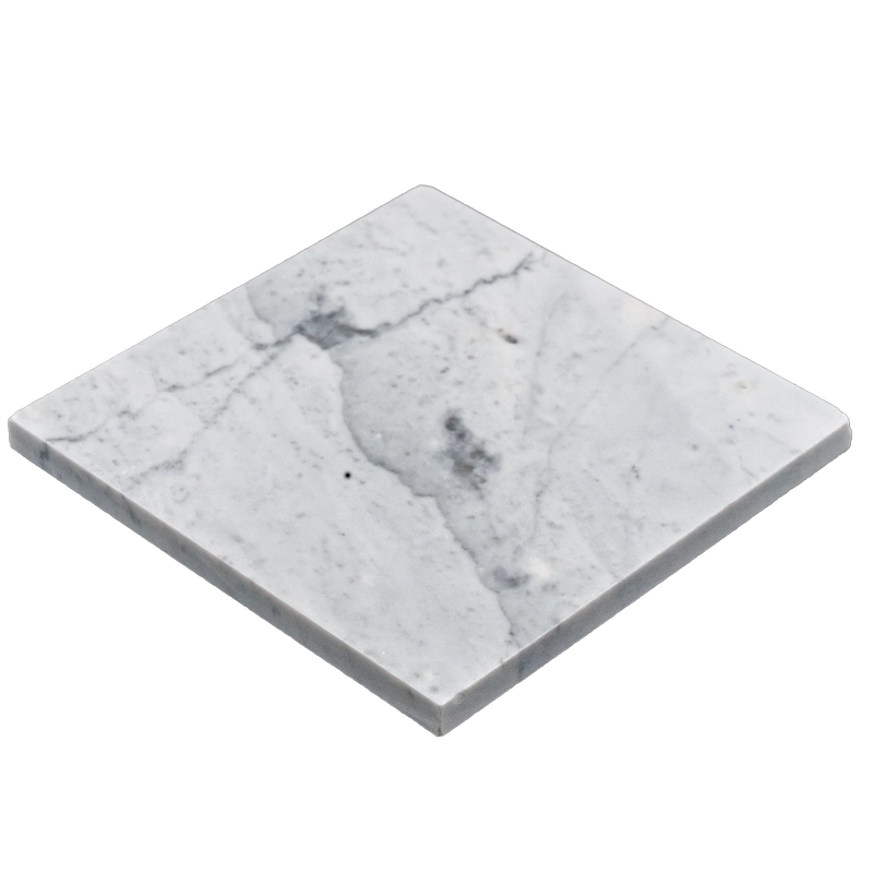 Close-up angled view of Carrara 6"x6" honed marble tile showing smooth surface and subtle veining across the grout line.