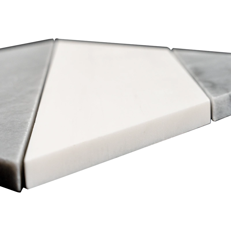 A close-up angled view of a white and gray marble mosaic tile sheet featuring a polished diamond pattern. The varying heights of the tiles reveal the craftsmanship and attention to detail, while the combination of gray veining and smooth white marble showcases the luxurious quality of the stone.