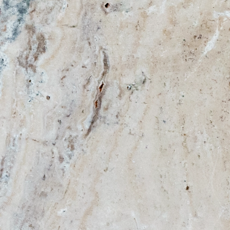 Close-up of Norwegian River 6"x12" tumbled travertine paver showing a warm beige/ivory base with flowing gray-taupe veining, scattered natural pits, and a soft matte texture.